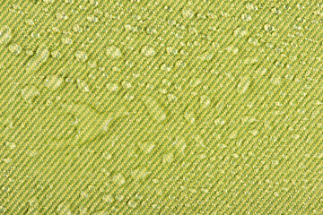 Waterproof clothing or upholstered furniture made from waterproof textiles. Drops of water on green...