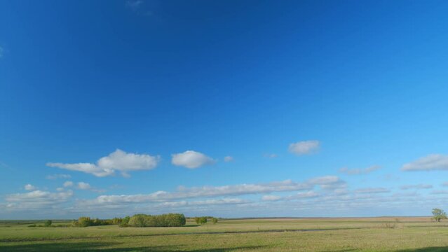 Mystic white clouds flying over green autumn field. Clouds fly across the blue sky. Timelapse.