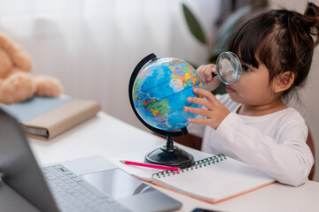Asian little girl is learning the globe model, concept of save the world and learn through play activity for kid education at home.