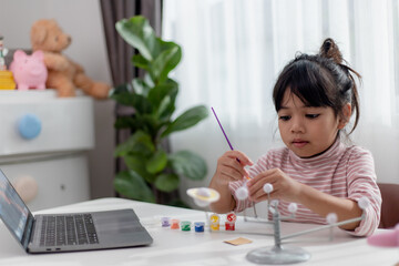 Asian Little girl studies the solar system in geography class. looking at the scale model of planets