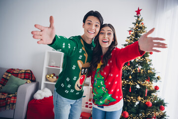 Photo of two positive funny partners raise opened arms invite you illumination lights house indoors