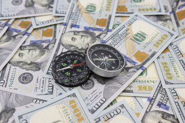 Classic navigational compass on the background of one hundred dollar bills