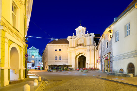 Night view of illuminated Ausros Vartu Street in the Old Town of Vilnius, Lithuania. Basilian Gate to Ukrainian Greek Catholic Monastery of the Holy Trinity on the right.