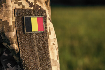 Close up millitary woman or man shoulder arm sleeve with Belgium flag patch. Belgium troops army, soldier camouflage uniform. Armed Forces, empty copy space for text
