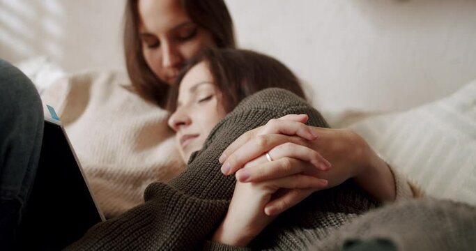 Couple of women hug each other warmly and relax at home in the bedroom. Romance and portrait of lesbian couple enjoying. LGBT rights, Lesbian family. Lifestyle and relationships. LGBT concept