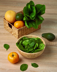 green fresh spinach leaves in wooden bowl on wooden background