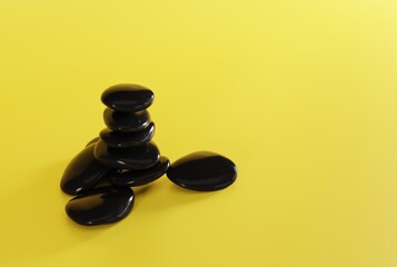 Black massage stones on a yellow background. The concept of massaging, realking. SPA and beauty care. 3D render, 3D illustration.