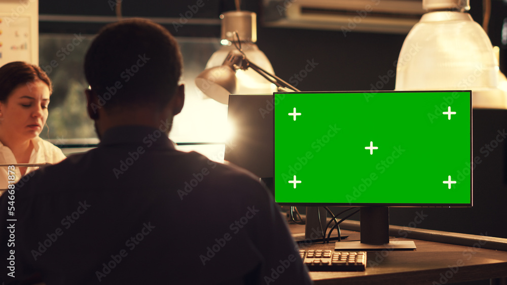 Poster freelancer looking at greenscreen display on computer, working with blank mockup template and copysp