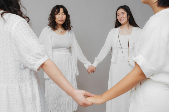 asian women stand in a circle holding hands