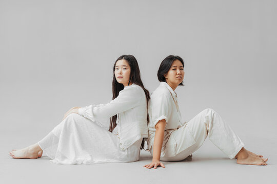 Different Asian women sitting back to back