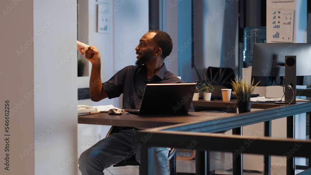 Poster office employee working on presentation late at night, creating professional startup report to devel
