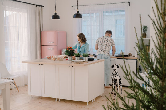 Woman and man preparing lunch at home in the pink stylish kitchen
