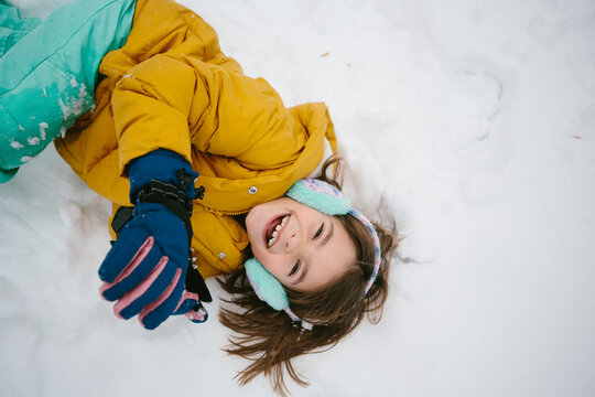 overhead view of happy girl laying in snow