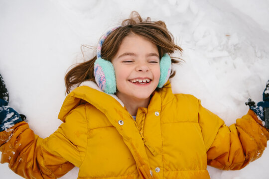 overhead view of happy girl laying in snow