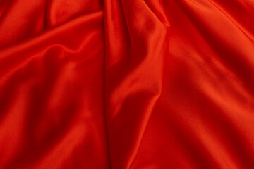 Texture of red satin fabric close-up. Silk or satin material. Textile background. Plain bright cloth