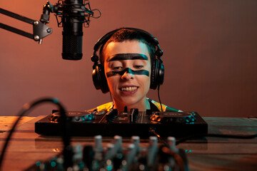 Musical artist acting funky looking at mixer, being focused on control buttons at dj turntables...