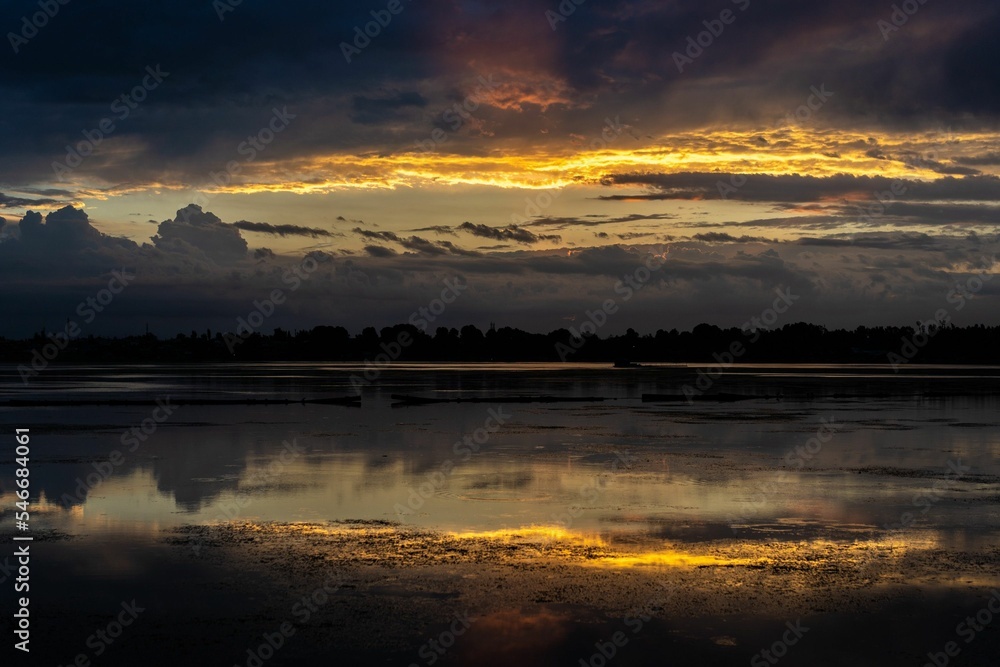 Poster scenic view of a calm lake with reflection of clouds and sunlight on the water surface