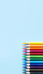 Pencils of different colors on blue background. Vertical art banner mockup for social media...