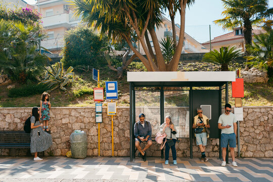 People waiting in bus stop checking their smartphones