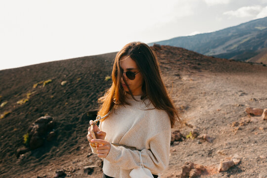 Woman on top of mountain taking a picture on smartphone