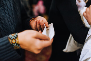 A man, dad, godfather holds a paper with the hair of a newborn child in his hands after the haircut ceremony in the church. Photography, religion.