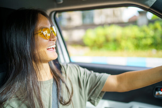 Young Asian woman laughing while going for car ride