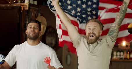 Friends at the bar in a pub having fun. Men with the flag of the national country of USA drinking beer and watching sport game. Happy mixed race supporters cheering and exulting after winning. - Powered by Adobe