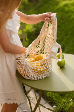 Little girl putting fruits into shopping bag