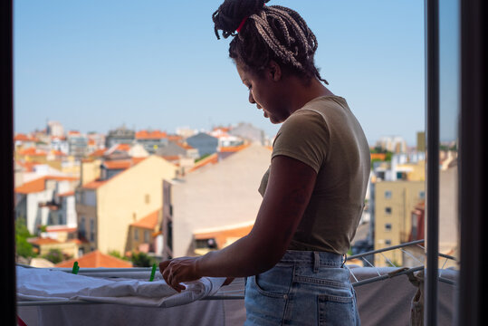 Young black real Woman doing laundry on balcony