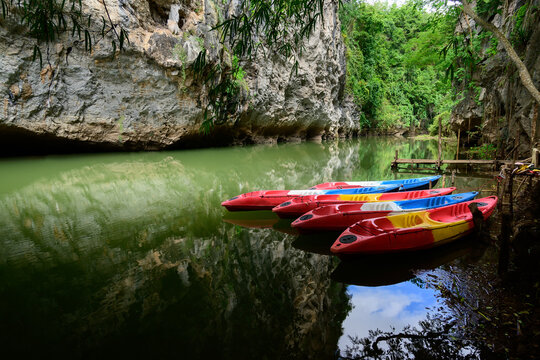 Red kayaks with paddles in them on river Tourist canoes with paddles on the river coast in summer at Pha Hob, Mae Moh, Thailand..