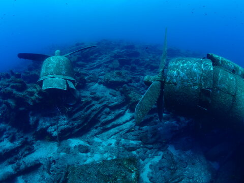scuba divers exploring airplane wreck underwater taking photos of c47