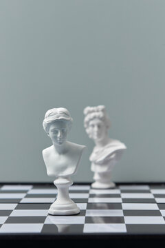 Vintage white gypsum busts on chessboard.