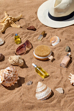 cosmetics bottles and seashells on sand with sun heat