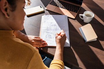 Hispanic female student making notes in notepad