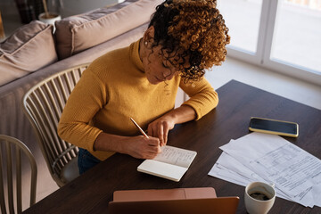 Focused businesswoman making list during work