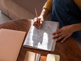 Crop student doing homework assignment in notebook