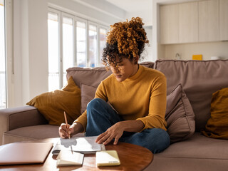 Hispanic woman sitting on sofa and studying