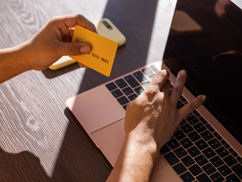 Crop woman with credit card typing on laptop keyboard