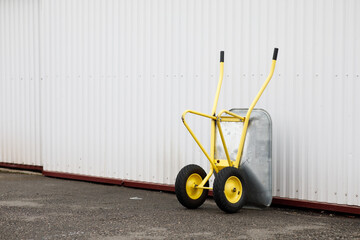 a yellow wheelbarrow stands by the wall