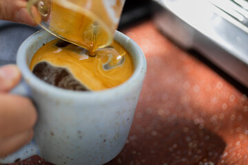 barista pouring espresso in a coffee mug