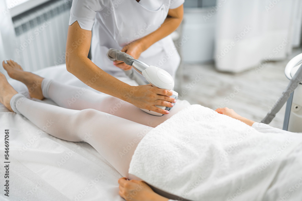 Sticker Non-surgical SPA treatment - endermologie. Unrecognizable Asian person during lipomassage on leg area. Reducing excess appearance of cellulite. High quality photo