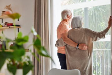 Anonymous aged couple looking out window together
