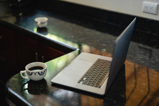 Image of a computer at a breakfast bar with a cup of coffee 