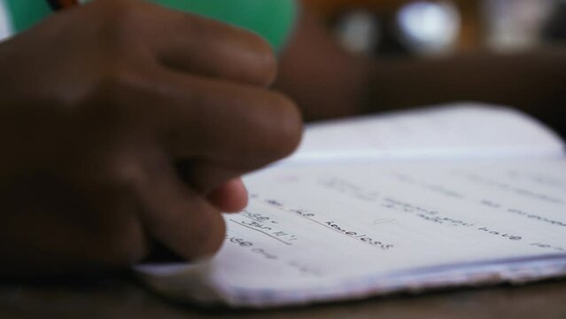 Close up of a person writing on the page of a paper workbook.