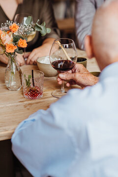 elderly man holding a glass of red wine at a gathering