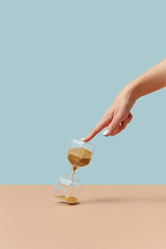 Hourglass touched by female hand.