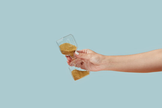 Hourglass with golden sand in woman's hand.