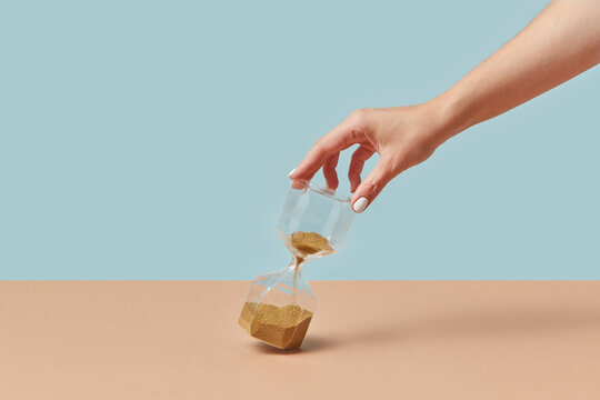 Sandglass with golden sand in female hand.