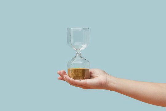 Hourglass with golden sand in woman's hand.