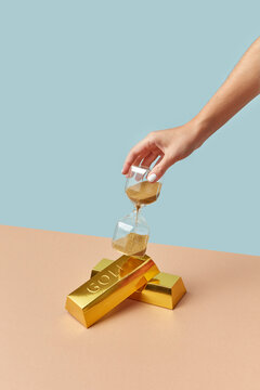 Golden bars and vintage hourglass in female hand.